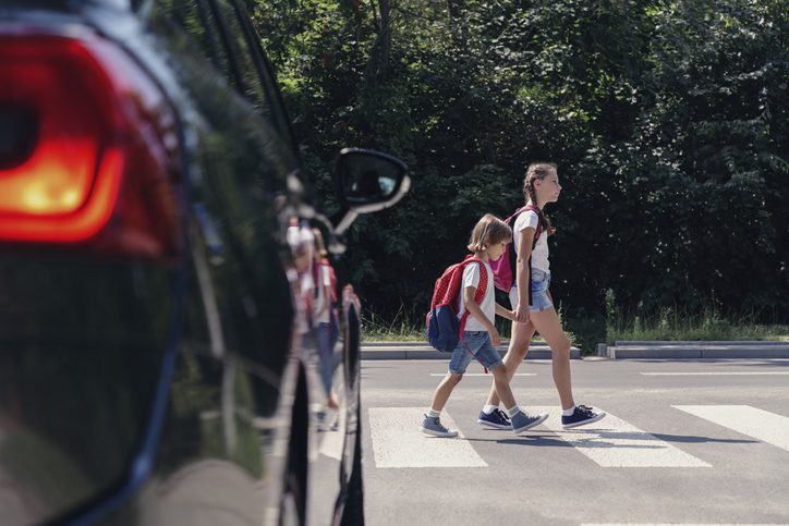 Children with backpacks crossing street crosswalk