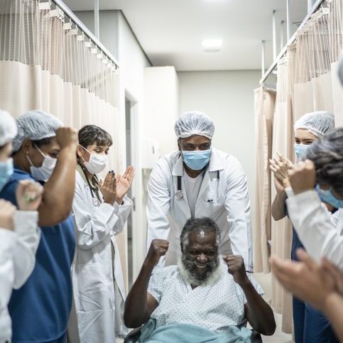Doctors and nurses celebrating senior man leaving the hospital after recovery